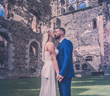Portrait de couple de mariés en lumière naturelle le jour de leur mariage s'embrassant au milieu de ruines